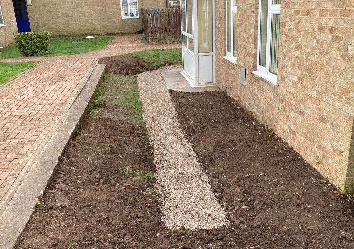 a french drainage system outside a property beside a path.