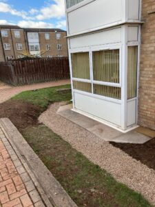 a newly installed drainage system with restored soil and pathway around it