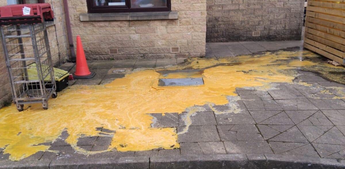 fat and grease overflowing from a manhole outside a commercial property.